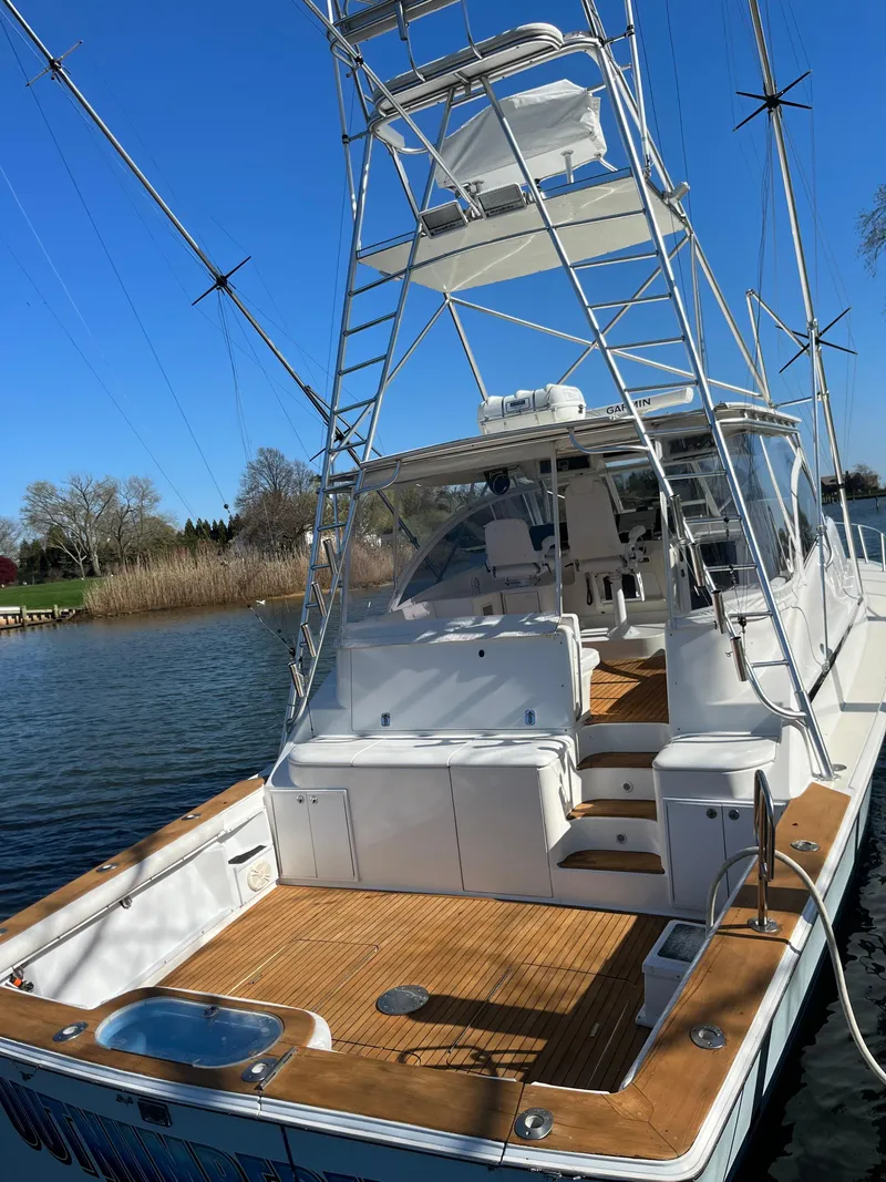 Slide: The Image of 1998 Ocean Yachts 48 Express boat with spacious deck and tower, docked on a sunny day. - 3