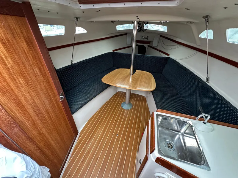 Slide: The Image of 2005 Catalina 250 MkII sailboat interior with wood finish, seating, and compact kitchen area. - 7