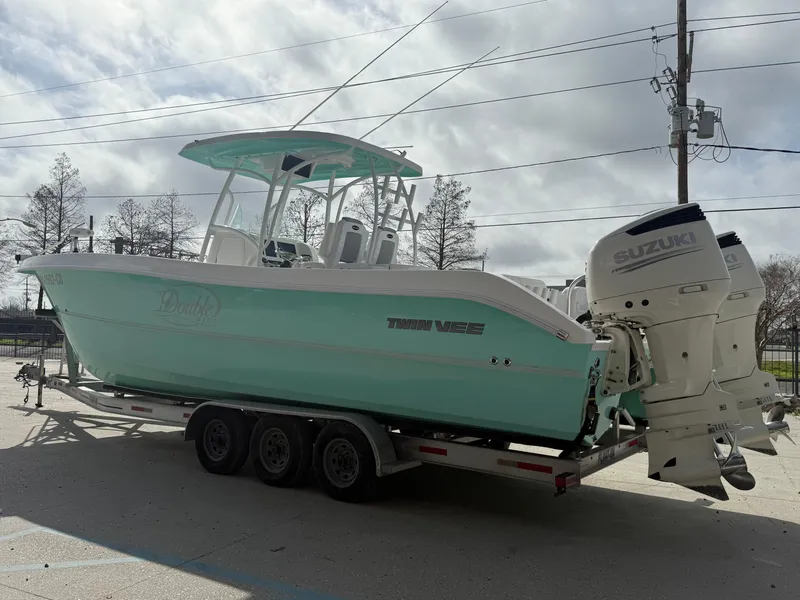 Slide: The Image of 2021 Twin Vee 310 GF boat on trailer with dual Suzuki engines, parked outdoors. - 11