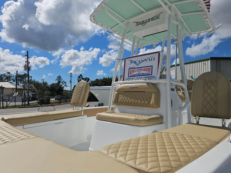 Slide: The Image of 2025 Savannah 210X boat with tan seating, under a blue sky with clouds. - 14
