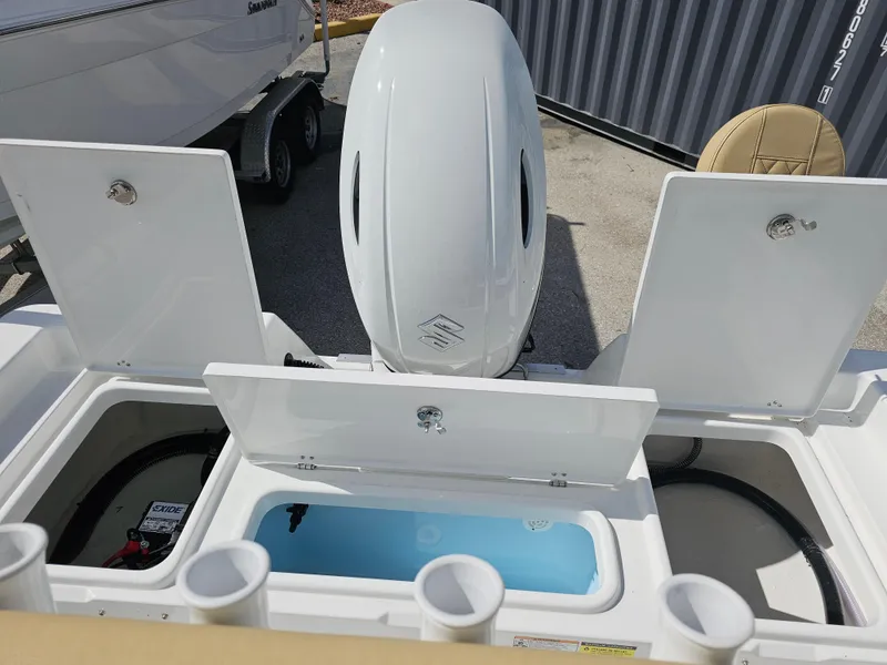 Slide: The Image of 2025 Savannah 210X boat with open storage compartments and outboard motor. - 19
