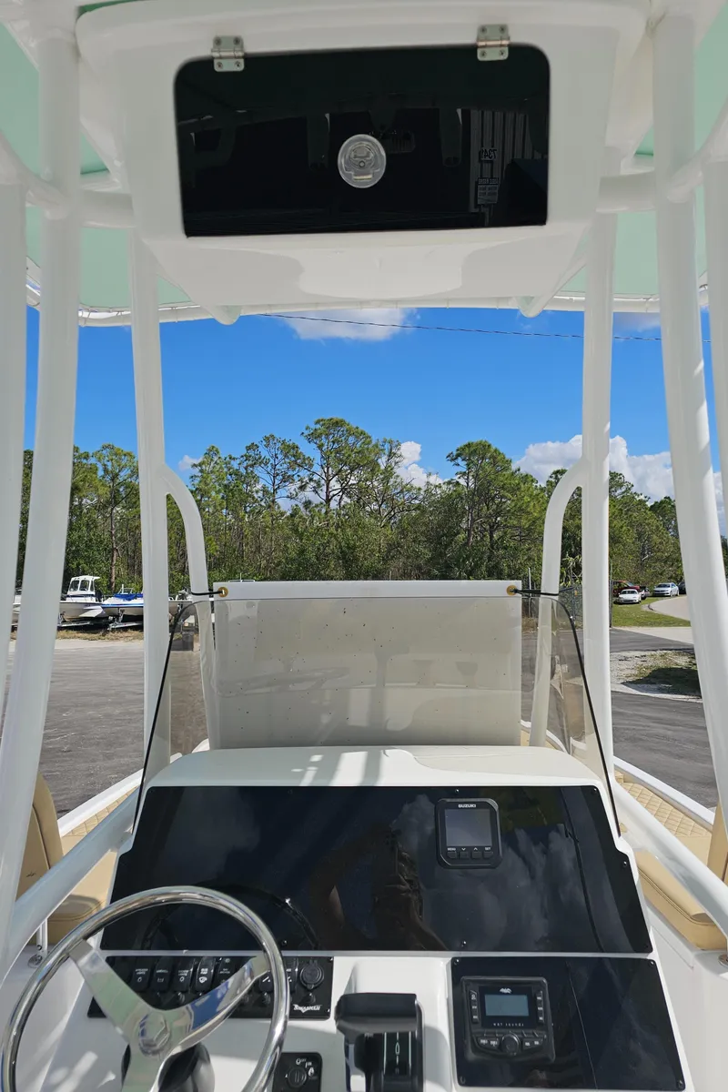 Slide: The Image of 2025 Savannah 210X boat cockpit with steering wheel and control panel, under clear blue sky. - 35