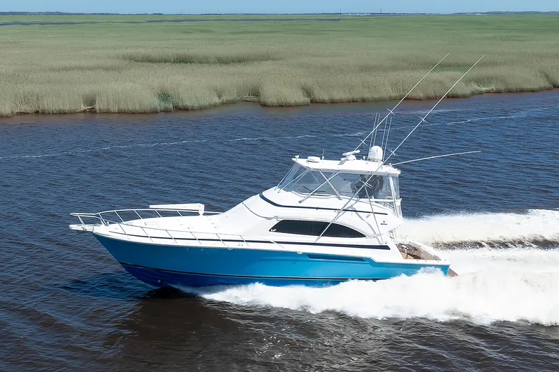 Slide: The Image of 2007 Bertram 570 Convertible yacht cruising on a river with lush green banks. - 16