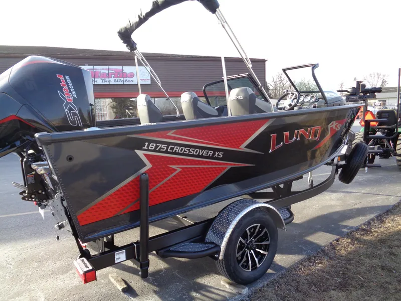 Slide: The Image of 2025 Lund 1875 Crossover XS boat on trailer, featuring sleek design and modern graphics. - 12