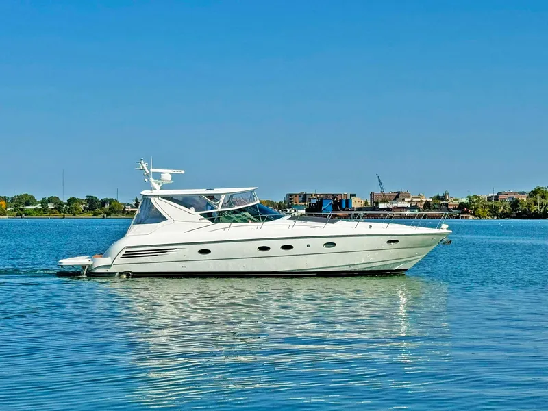 The Image of 1998 Trojan 440 Express yacht cruising on a calm, blue waterway. - 1