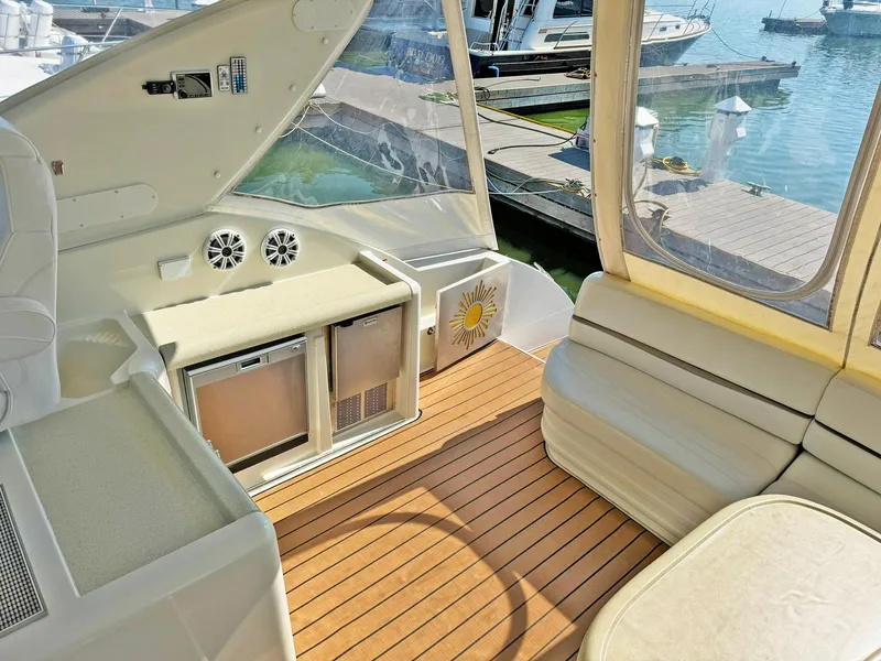 Slide: The Image of Interior of 1998 Trojan 440 Express yacht with seating and mini fridge, dockside view. - 13