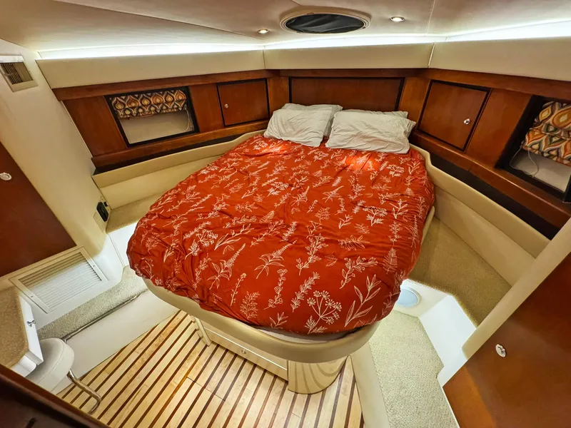 Slide: The Image of Cozy cabin interior of a 1998 Trojan 440 Express yacht with a red bedspread. - 39