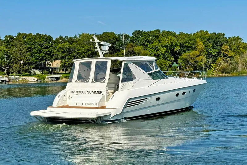 Slide: The Image of 1998 Trojan 440 Express yacht cruising on a serene lake with lush green trees. - 4