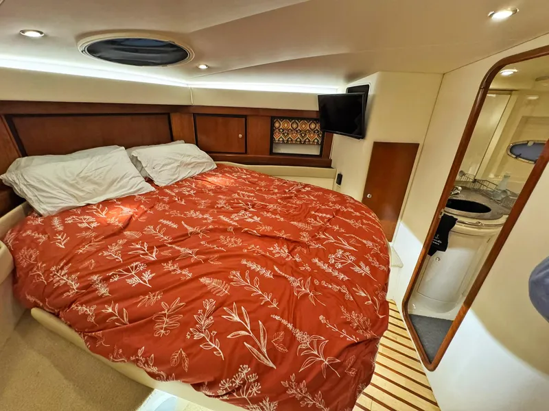 Slide: The Image of 1998 Trojan 440 Express yacht cabin with bed, red floral bedding, and TV. - 41