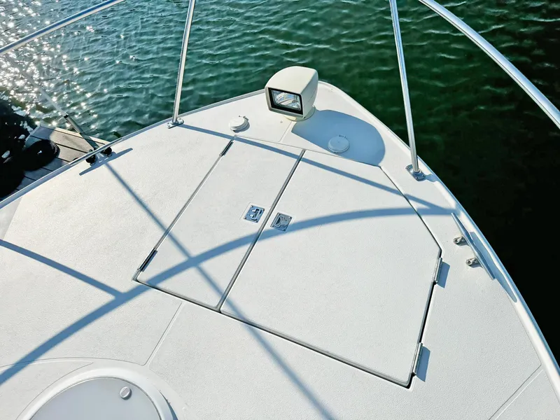 Slide: The Image of Bow of 1998 Trojan 440 Express boat with hatch and spotlight on calm water. - 9