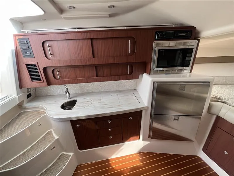 Slide: The Image of 2015 Grady-White Express 370 interior with kitchenette, wood cabinetry, and stainless steel appliances. - 15