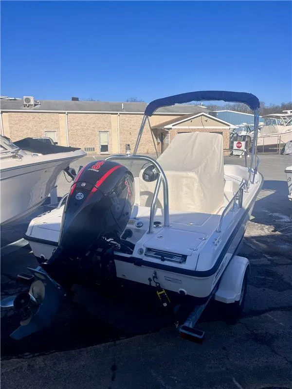 Slide: The Image of 2008 Boston Whaler 180 Dauntless boat with outboard motor and canopy, parked outdoors. - 10