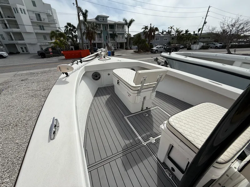 Slide: The Image of 2021 C-Hawk 25 Center Console boat with spacious deck and seating, docked near coastal buildings. - 11
