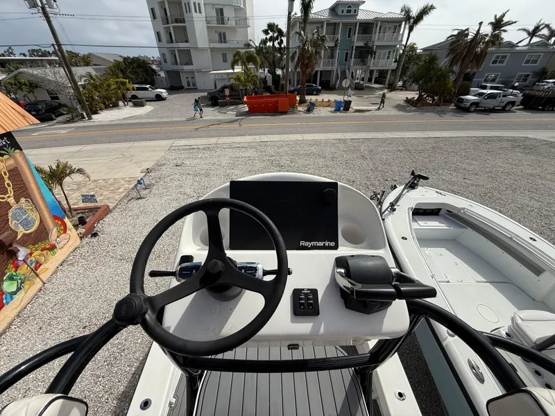 Slide: The Image of C-Hawk 25 Center Console 2021 boat with steering wheel and Raymarine display, docked near buildings. - 17