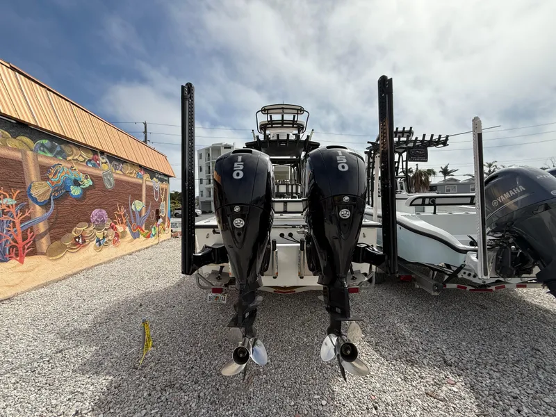 Slide: The Image of C-Hawk 25 Center Console 2021 with dual outboard motors, parked on gravel near mural. - 2