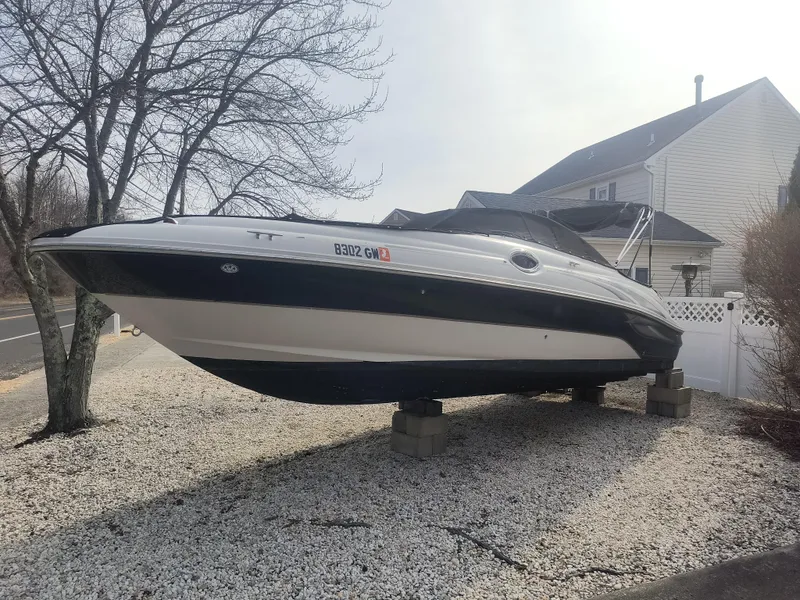 The Image of 2004 Sea Ray 240 Sundeck boat on blocks in a residential yard. - 1