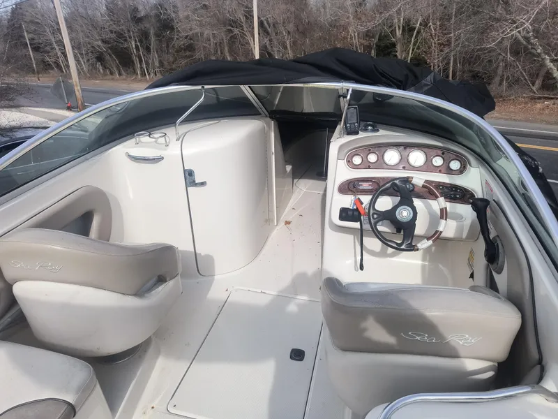Slide: The Image of 2004 Sea Ray 240 Sundeck interior with steering wheel and seating, parked outdoors. - 5