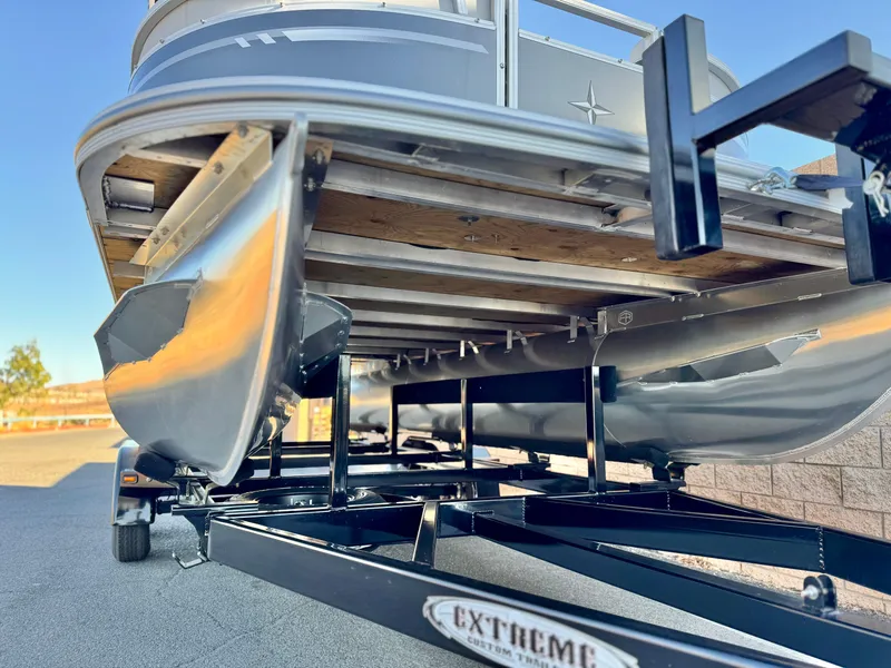Slide: The Image of 2025 Berkshire 20 CRSE pontoon boat on trailer, showcasing undercarriage and pontoons. - 3