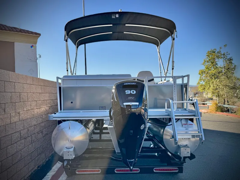 Slide: The Image of 2025 Berkshire 20 CRSE pontoon boat with canopy and outboard motor, parked outdoors. - 4