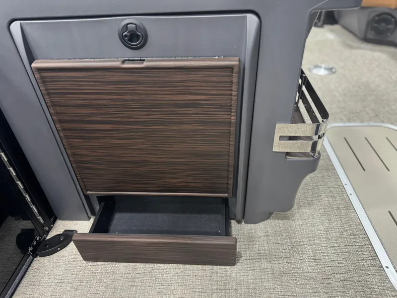Slide: The Image of 2025 Bennington 24 MFB boat storage compartment with tan cushion and visible battery setup. - 19