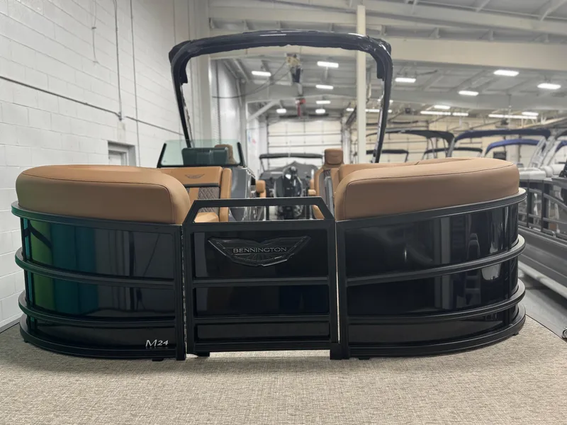 Slide: The Image of 2025 Bennington 24 MFB pontoon boat with sleek black design and tan seating in showroom. - 3