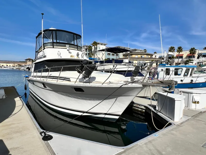 Slide: The Image of 1982 Silverton 37 Convertible yacht docked at marina under clear blue sky. - 1