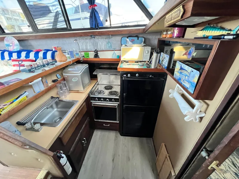 Slide: The Image of 1982 Silverton 37 Convertible boat kitchen with stove, sink, and compact appliances. - 12