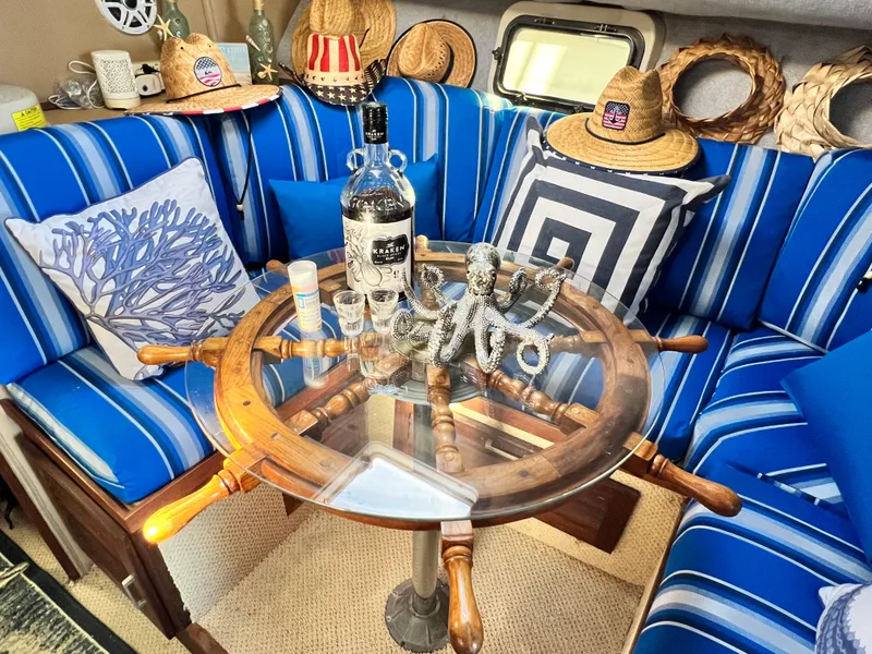 Slide: The Image of 1982 Silverton 37 Convertible interior with nautical decor, blue-striped seating, and ship wheel table. - 17