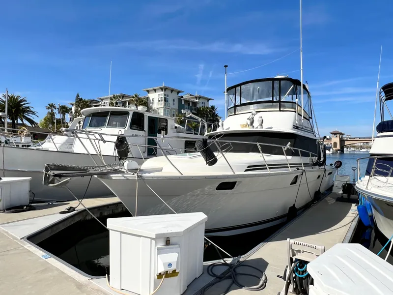 Slide: The Image of 1982 Silverton 37 Convertible yacht docked at marina under clear blue sky. - 2