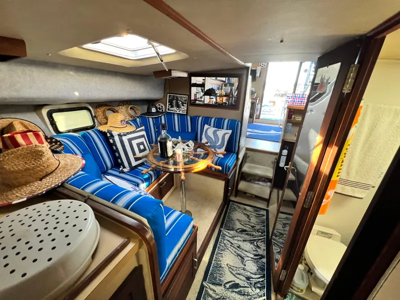 Slide: The Image of 1982 Silverton 37 Convertible interior with blue-striped seating, dining table, and nautical decor. - 22