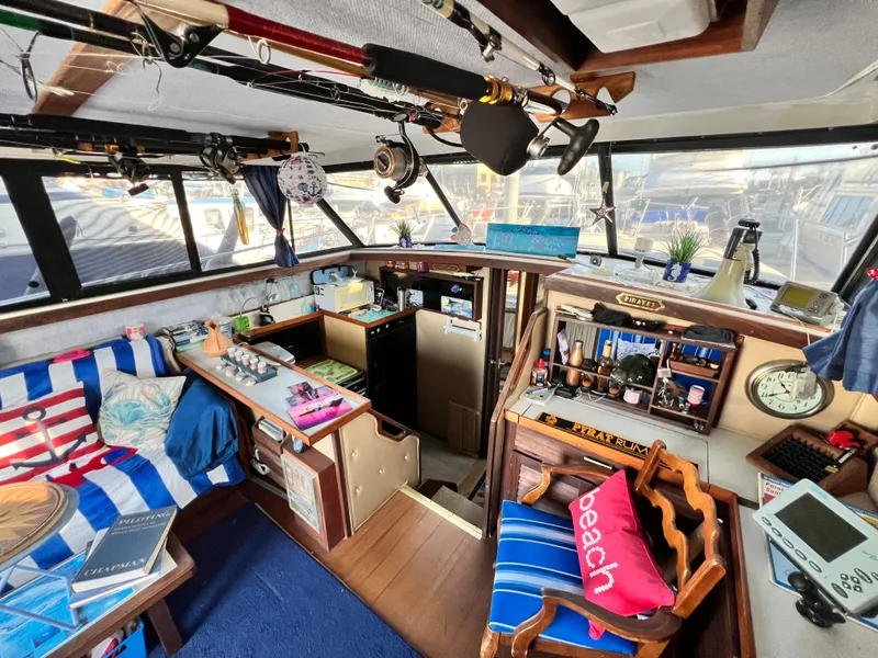 Slide: The Image of 1982 Silverton 37 Convertible boat interior with cozy seating, fishing rods, and nautical decor. - 5