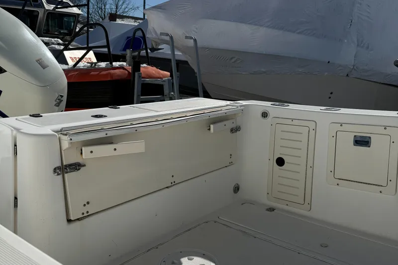 Slide: The Image of 2000 Mako 253 Walk Around boat interior, featuring storage compartments and seating area. - 11