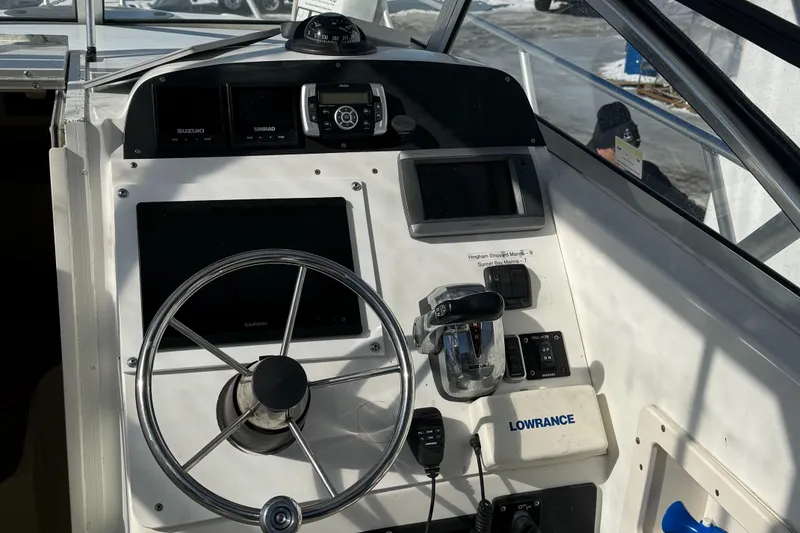 Slide: The Image of 2000 Mako 253 Walk Around boat dashboard with steering wheel and navigation equipment. - 14