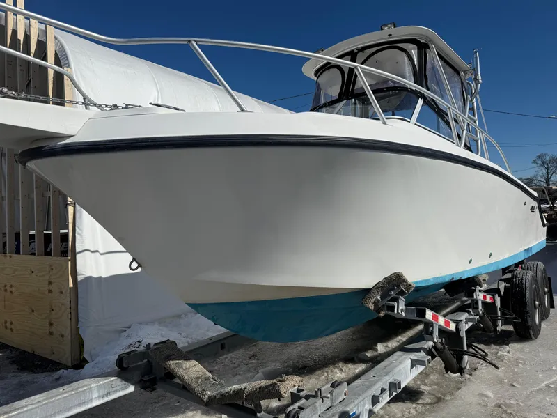 Slide: The Image of 2000 Mako 253 Walk Around boat on trailer, white hull, blue bottom, outdoor setting. - 3