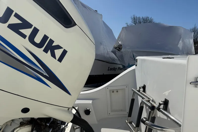 Slide: The Image of Mako 253 Walk Around 2000 boat with Suzuki engine, partially covered, in storage. - 6