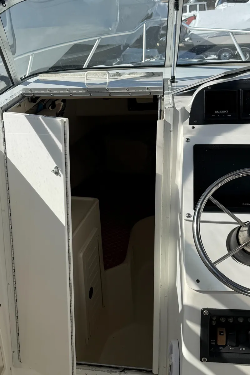 Slide: The Image of 2000 Mako 253 Walk Around boat interior with steering wheel and cabin entrance. - 9