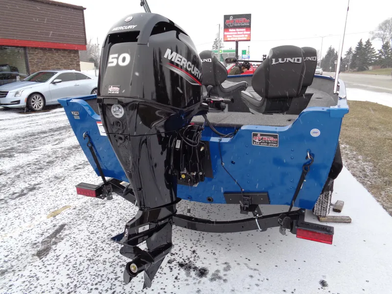 Slide: The Image of 2024 Lund 1650 Angler Tiller boat with Mercury 50 HP outboard motor, parked on snowy ground. - 5