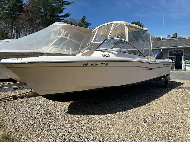 Slide: The Image of 2014 Grady-White 225 Freedom boat on gravel, covered, with trees and building in background. - 2