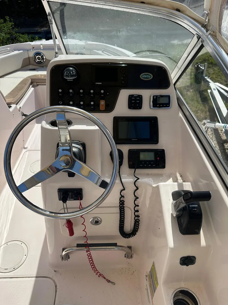 Slide: The Image of 2014 Grady-White 225 Freedom boat dashboard with steering wheel and navigation controls. - 4