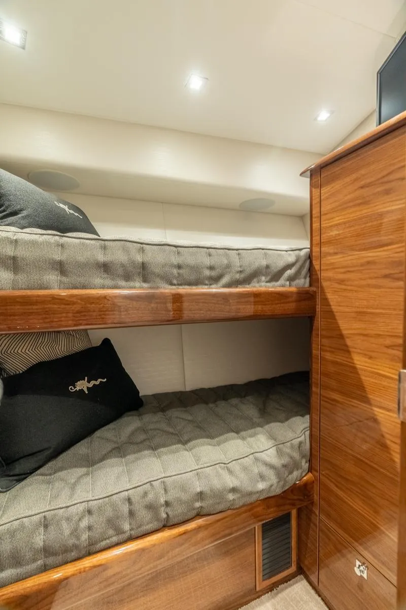 Slide: The Image of Bunk beds in 2025 Viking 64 Convertible yacht cabin, featuring wood finish and modern lighting. - 19