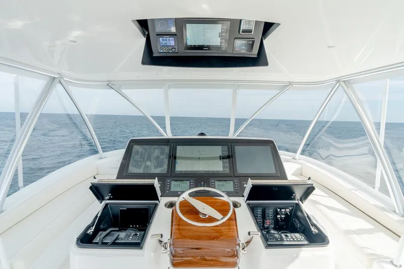 Slide: The Image of 2025 Viking 64 Convertible yacht helm with advanced navigation systems, steering wheel, and ocean view. - 7