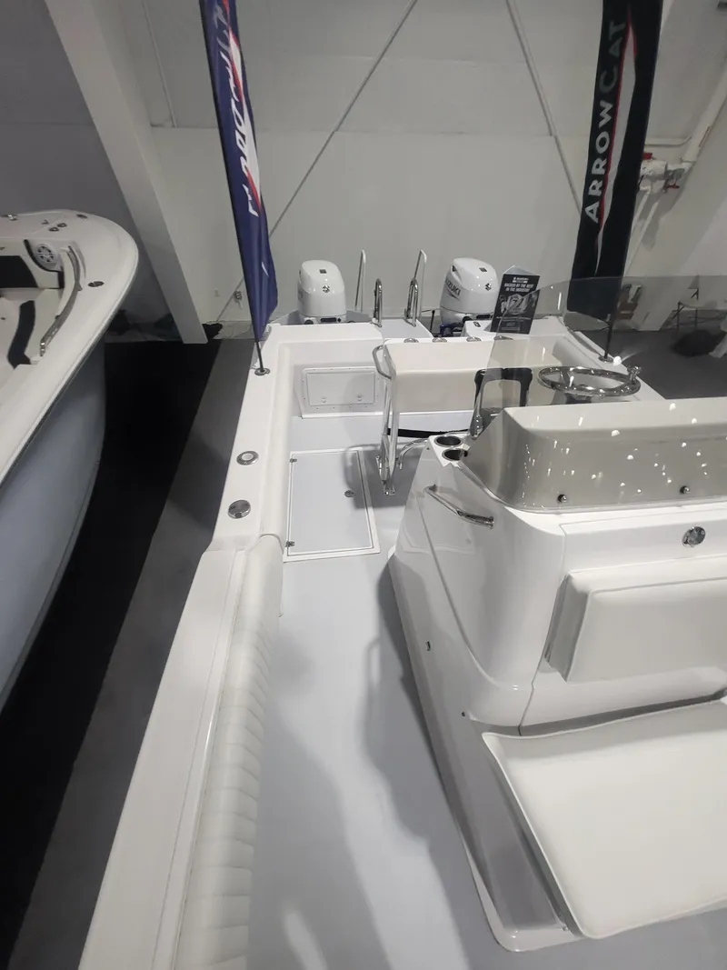 Slide: The Image of 2025 ArrowCat 20CC boat interior with seating and controls at a showroom. - 9