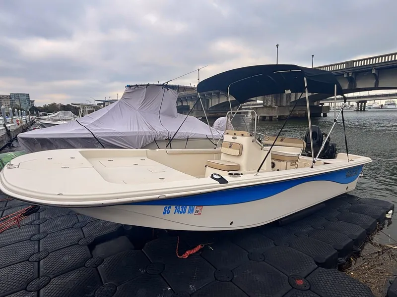 Slide: The Image of 2020 Carolina Skiff 21 LS boat docked by a bridge under cloudy skies. - 1