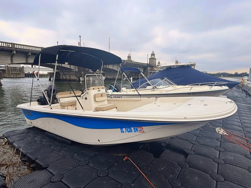 Slide: The Image of 2020 Carolina Skiff 21 LS boat docked by a bridge on a cloudy day. - 2