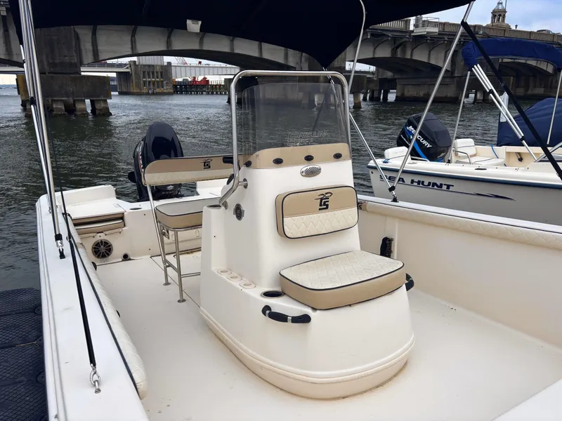 Slide: The Image of 2020 Carolina Skiff 21 LS boat docked near a bridge, featuring a central console. - 3