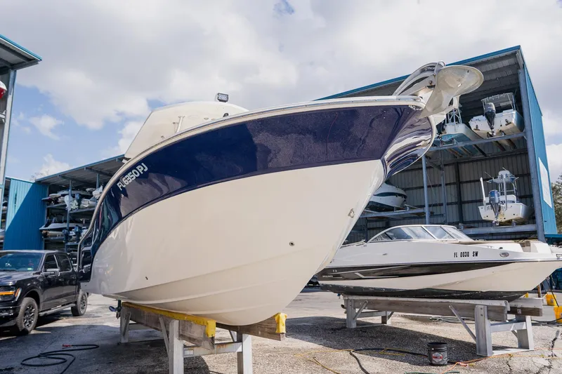 Slide: The Image of 2012 Sea Fox 286 Commander boat on dry dock, blue and white hull, sunny day. - 27