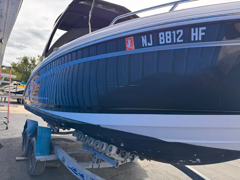 Slide: The Image of Chaparral 257 SSX 2013 boat with black cover, docked near blue marine supply building. - 2