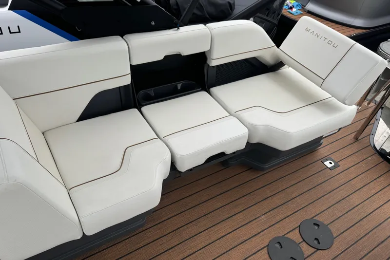 Slide: The Image of 2025 Manitou 24' Explore Switchback boat seating with white upholstery and wooden deck. - 10