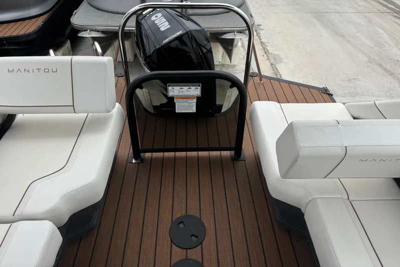Slide: The Image of 2025 Manitou 24' Explore Switchback boat interior with seating and outboard motor. - 11
