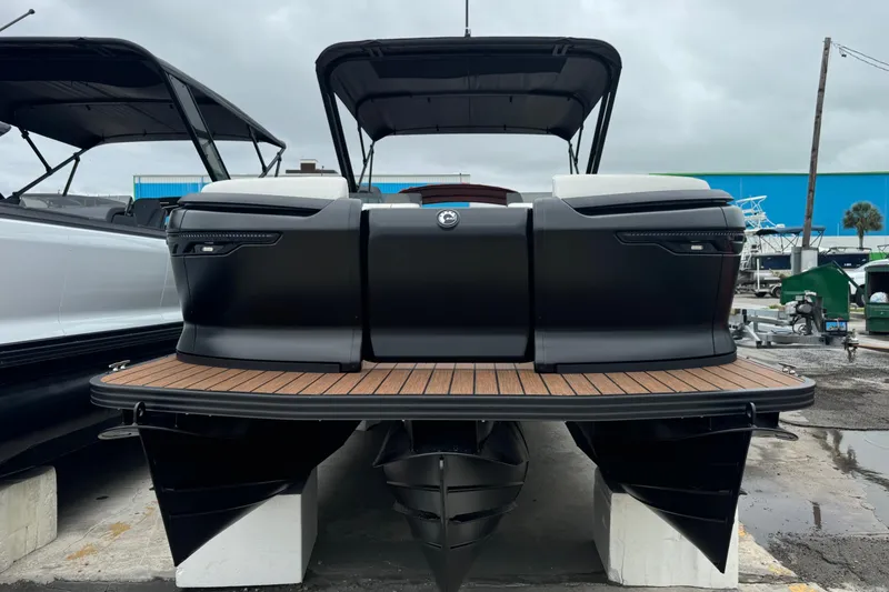 Slide: The Image of 2025 Manitou 24' Explore Switchback pontoon boat with sleek black design and wooden deck. - 2